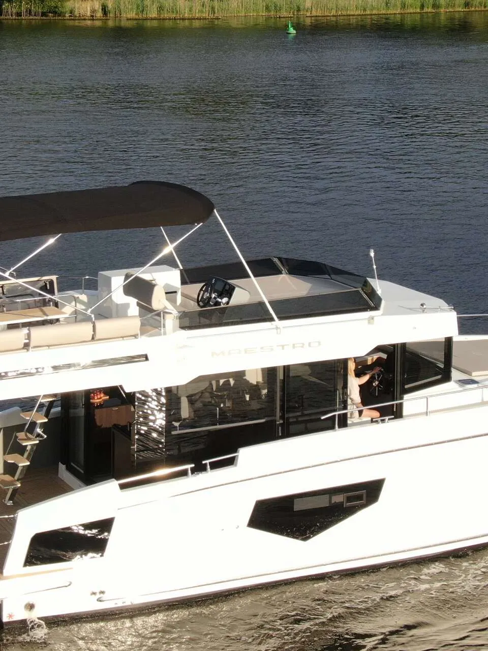 Een witte motorboot met twee dekken vaart op het water, met een zwarte bimini op het bovendek. — Cobra Yachts Maestro 42