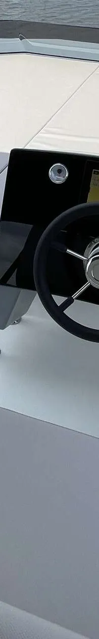 Een bovenaanzicht van de cockpit van een boot met een stuurwiel, navigatiescherm en grijze kussens. — Cobra Yachts Maestro 42