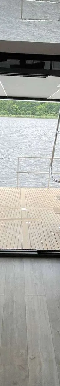 Een interieur van een boot met een keukenblok, zitbanken en uitzicht op water en beboste oever. — Cobra Yachts Maestro 42