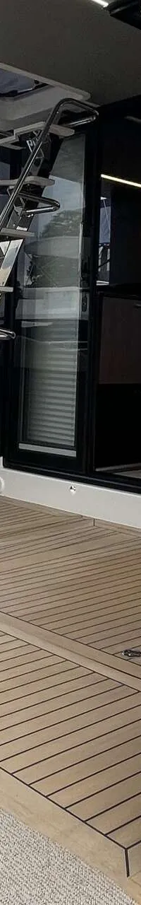 Een jacht met een teakhouten dek, een trap naar een bovendek en een glazen schuifdeur naar de kajuit.