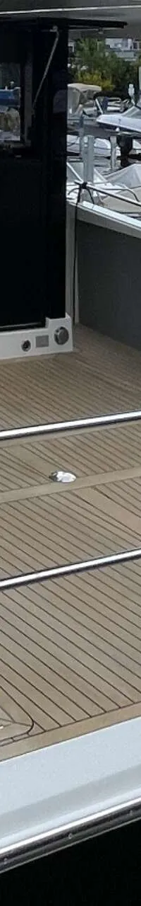 Een witte boot met een houten dek en een zilveren reling ligt aangemeerd aan een steiger. — Cobra Yachts Maestro 42