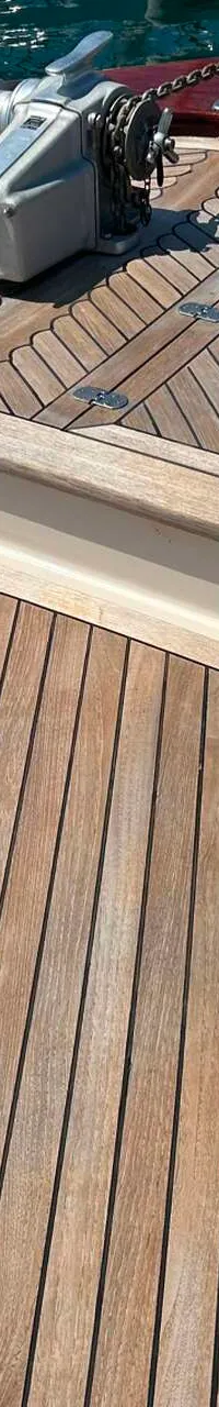 De foto toont het voordek van een boot met een houten dek, een ankerlier en touwen. — Apreamare 12 Cabinato