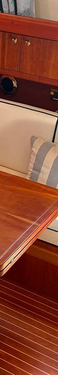 Een interieur van een boot met een houten vloer, een tafel, een bank met kussens en een kombuis. — Apreamare 12 Cabinato