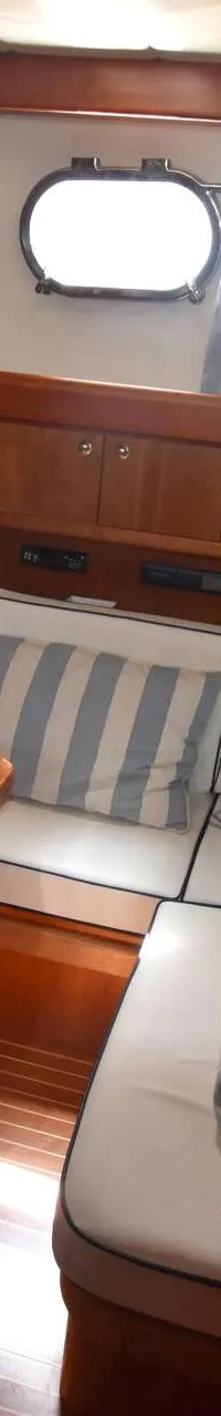 Een houten interieur met een zithoek, een tafel, een kombuis en patrijspoorten.