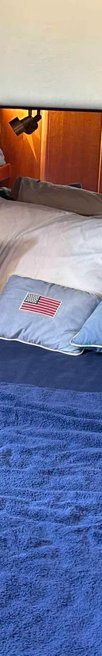 Een kajuit met een bed, blauw beddengoed, kussens en houten kasten. — Apreamare 12 Cabinato