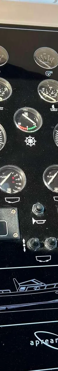 Een gedetailleerde foto van een dashboard met diverse meters, schakelaars en Raymarine-apparatuur.