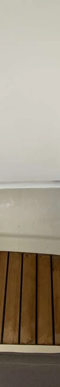 Een open opbergruimte met een houten vloer en een witte klep die openstaat.