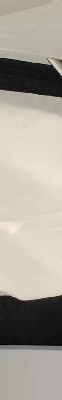 Een deel van een boot met een zwart-wit afdekzeil en metalen stangen, met water en een andere boot op de achtergrond.