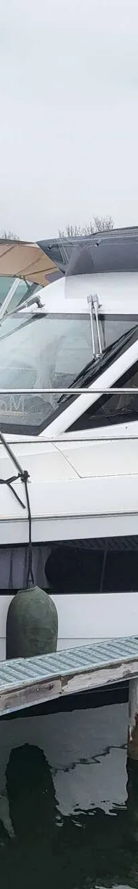Een witte motorboot met zwarte ramen en een zwarte kap ligt aangemeerd aan een steiger. — Galeon 300 Fly