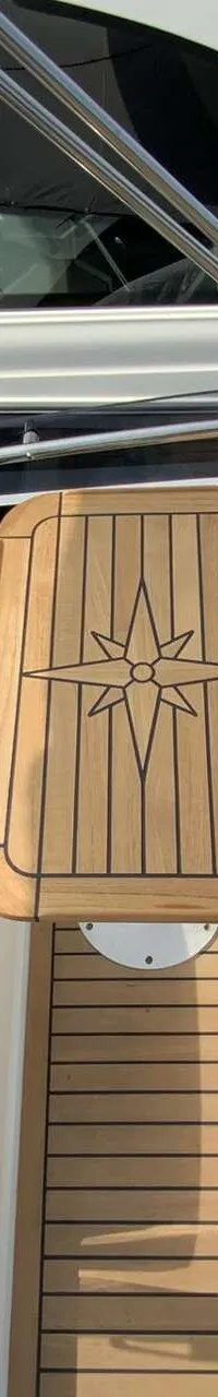 Een bovenaanzicht van een boot met een houten tafel met een kompasroos, omringd door bruine kussens. — Galeon 300 Fly