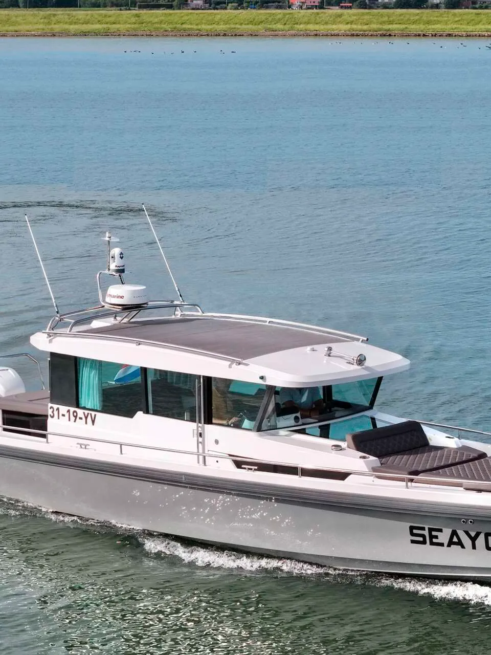 Een grijze motorboot met witte opbouw, registratie 31-19-YV en de naam SEAYOU2, vaart op blauw water. — Axopar 37 AC