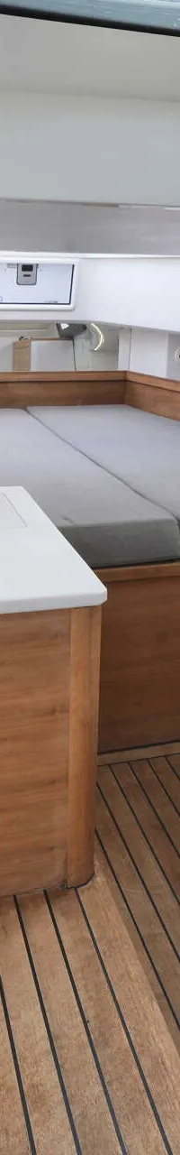 De foto toont een kajuit met een bed, houten vloer, ramen en een koelbox. — Axopar 37 AC