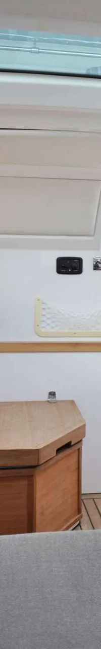 De foto toont het interieur van een boot met een koelbox, houten kasten, een bank en een glazen dak. — Axopar 37 AC