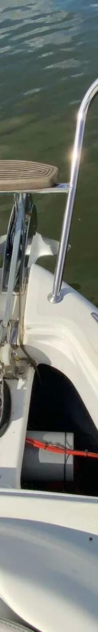 De boeg van een witte boot met een ankerlier, anker en reling, gezien vanaf de boot. — Saver 750 Cabin