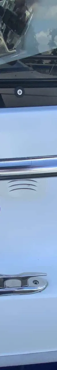 Een witte boot met blauwe accenten, een raam en een reling, met de tekst "cabin" en het logo van "DE VALK YACHT BROKERS".