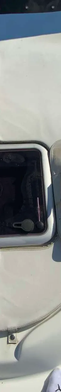 Een bovenaanzicht van het voordek van een witte boot met een open luik en een afdekhoes ernaast. — Saver 750 Cabin