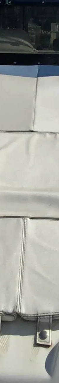 De foto toont de boeg van een witte boot met een wit kussen en een voorruit, met een logo van "DE VALK YACHT BROKERS"…