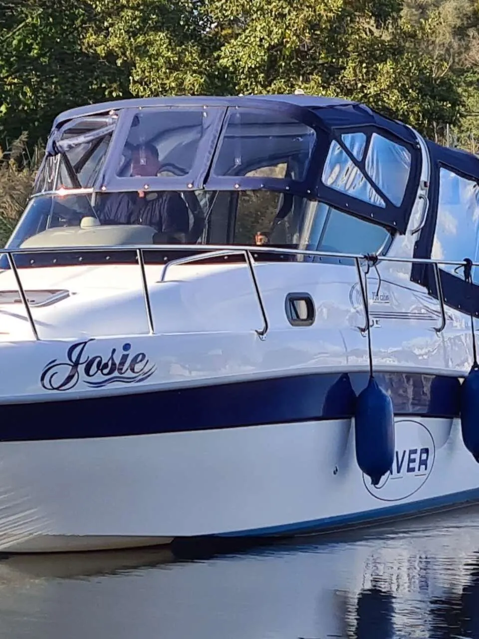 Een witte motorboot met blauwe accenten en de naam "Josie" op de boeg, vaart op het water. — Saver 750 Cabin
