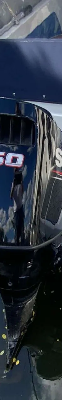 Een witte boot met een zwarte buitenboordmotor van 150 pk, liggend in het water naast een kade. — Saver 750 Cabin