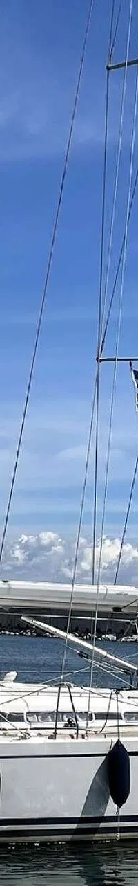 Een witte zeilboot met een grijze buiskap en stootwillen ligt in het water onder een blauwe lucht. — Arcona 430