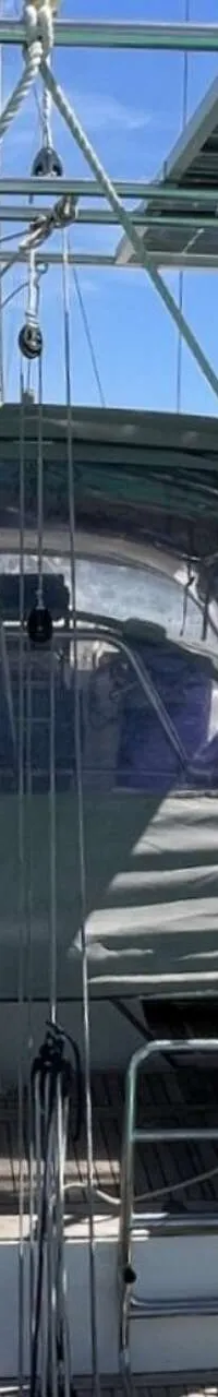 De achterkant van een witte zeilboot met een grijze buiskap, een Honda buitenboordmotor en zonnepanelen. — Arcona 430