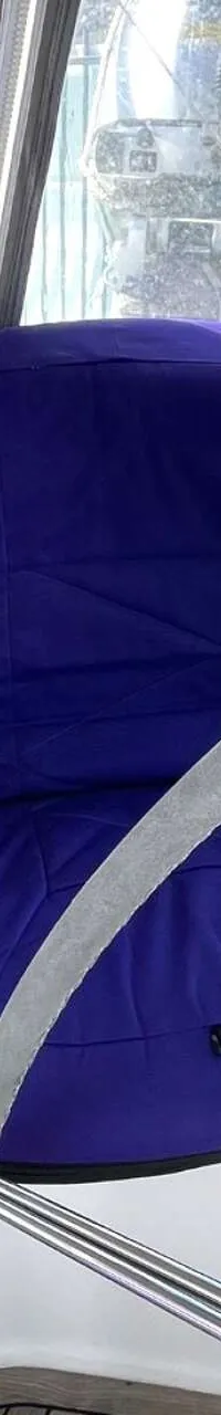 Een paarse stoel met een houten dek en een reling met een blauwe romp op de achtergrond.