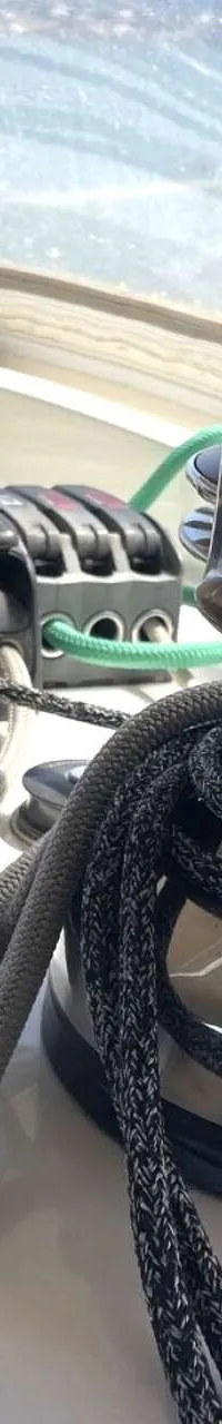 Een lier met touwen en een set stoppers op een wit dek, met Raymarine-instrumenten op de achtergrond.