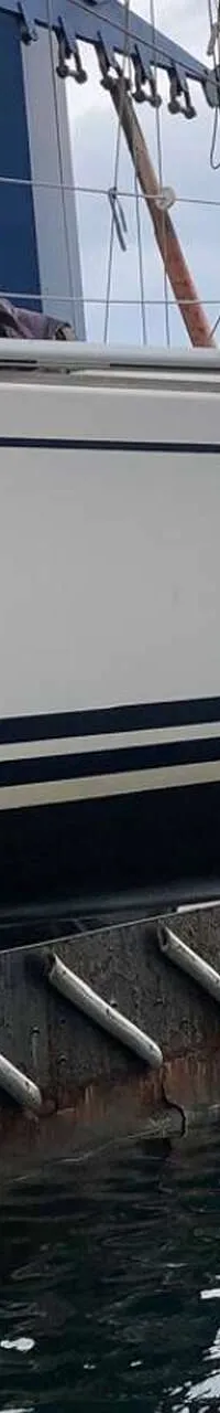 Een witte boot met een grijze buiskap en een transparant voorraam, liggend aan een kade met gebouwen op de achtergrond.