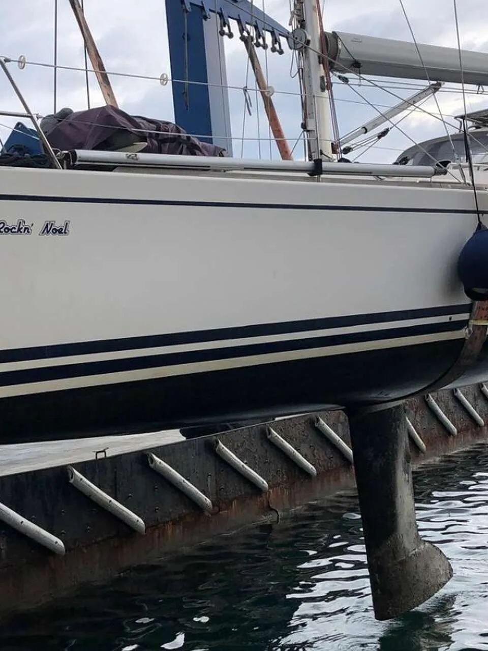 Een witte boot met een grijze buiskap en een transparant voorraam, liggend aan een kade met gebouwen op de achtergrond.