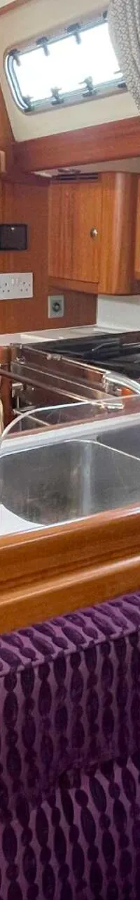 De foto toont een interieur van een boot met een kombuis, een paarse bank, een trap en een slaapcabine. — Arcona 430
