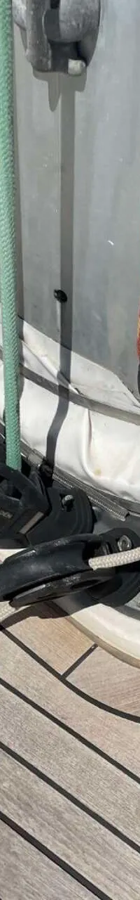 Een dek van een boot met een mastvoet, diverse lijnen, blokken en een luik, met de tekst "KEEP OFF" op de zijkant.