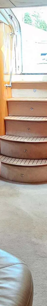 De foto toont het interieur van een boot met een zithoek, een tafel, een trap en houten kasten. — Sunseeker Portofino 53