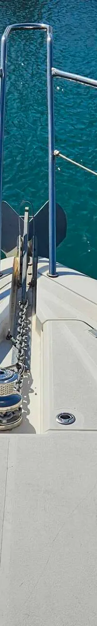 De boeg van een witte boot met een ankerlier, anker en reling, liggend in helder blauw water. — Sunseeker Portofino 53