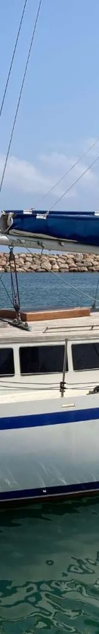 Een witte zeilboot met blauwe strepen ligt in het water, met een Yamaha buitenboordmotor aan de spiegel. — Endurance 44