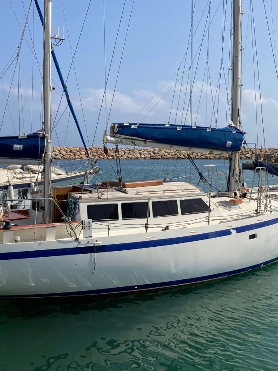 Een witte zeilboot met blauwe strepen ligt in het water, met een Yamaha buitenboordmotor aan de spiegel. — Endurance 44