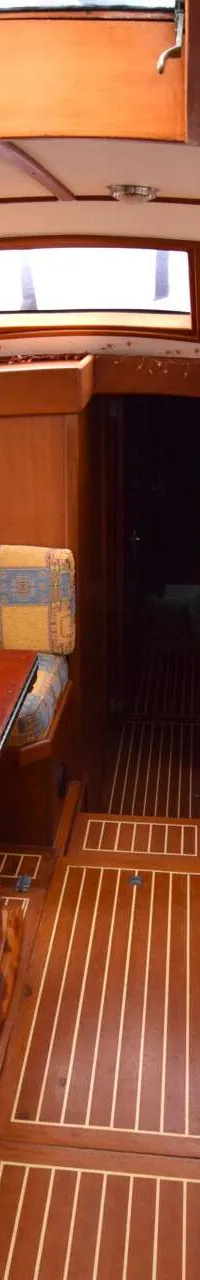 De foto toont het interieur van een boot met houten afwerking, een tafel, banken met kussens en ramen. — Endurance 44
