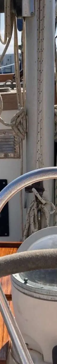 Een stuurwiel met kompas en een houten dashboard met diverse meters zijn zichtbaar in de kuip van een zeilboot.