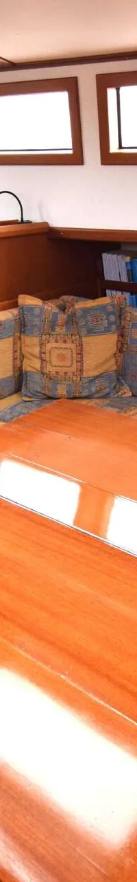 Een interieur van een boot met een houten tafel, banken met geel-blauwe kussens, en ramen. — Endurance 44