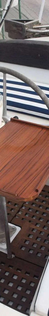 Een houten tafel met een kompas erop, omringd door gestreepte kussens en een houten rooster op de vloer.