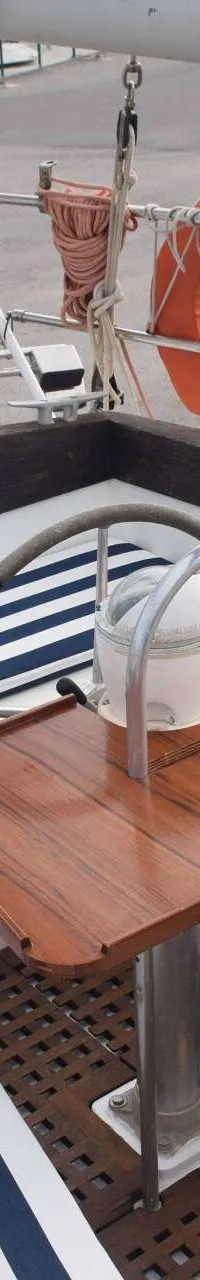 Een bootkuip met blauw-wit gestreepte kussens, een houten tafel en een kompas.