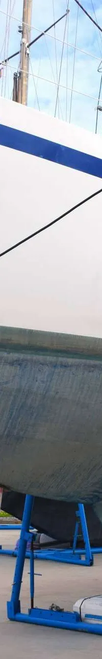 Een witte zeilboot met blauwe strepen en een blauwe onderkant staat op blauwe bokken op een kade. — Endurance 44
