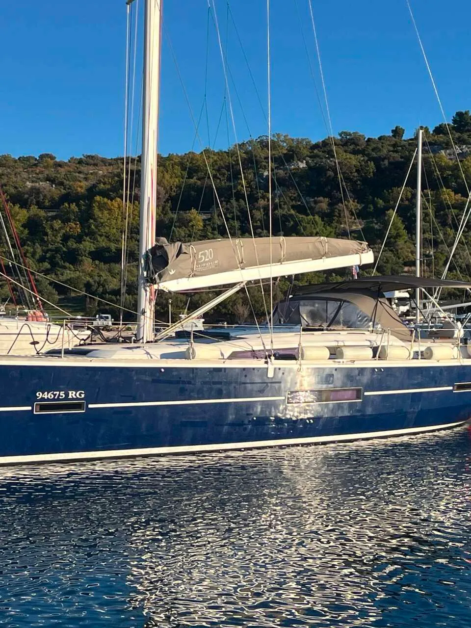 Een blauwe zeilboot met de naam "NOTUS" en registratienummer "94675 RG" ligt in het water. — Dufour 520 Grand Large
