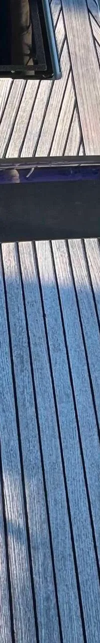 Een houten dek met twee luiken en een donkerblauwe strook met een paarse tint.