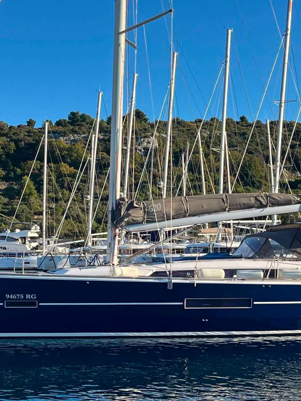 Een donkerblauwe zeilboot met de naam "NOTUS" en registratienummer "94675 RG" ligt in het water. — Dufour 520 Grand Large