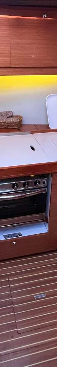 De foto toont een kombuis met een oven, spoelbak, koelkast en een zitbank met witte kussens.