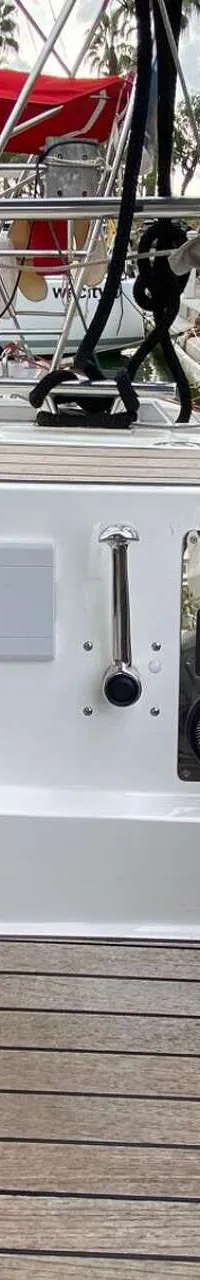 Een deel van het dek van een zeilboot met houten vloer en een wit paneel met diverse meters en schakelaars.