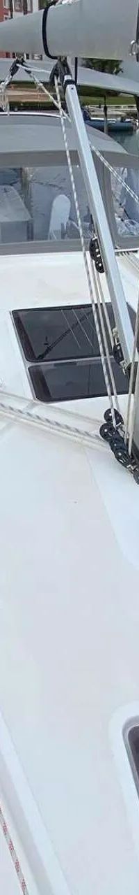 Een witte zeilboot ligt in een jachthaven, met een grijze buiskap en een mast in het midden. — Bavaria 34 Cruiser