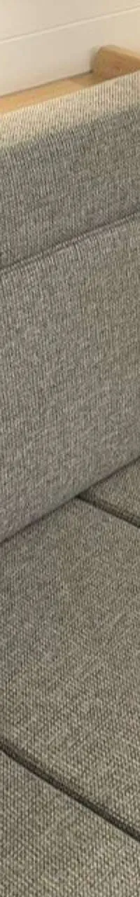 Een grijze stoffen bank met houten afwerking en een zwart apparaat op een plankje.