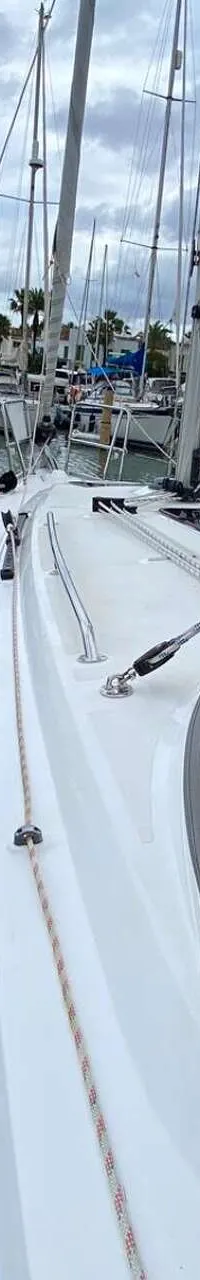 Een witte zeilboot ligt in een jachthaven met een grijze buiskap en een opgerold zeil op de giek. — Bavaria 34 Cruiser