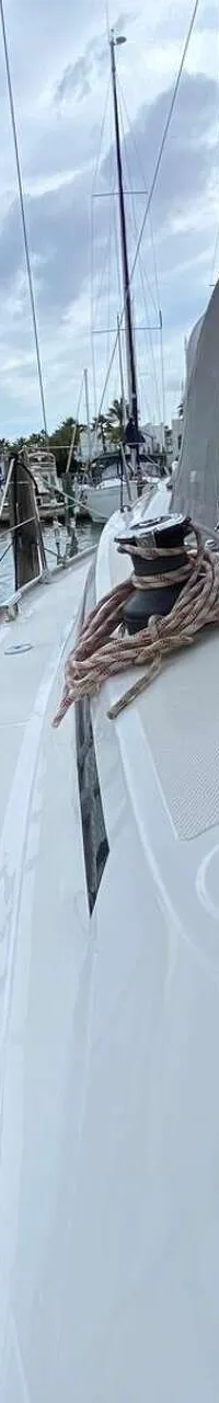 Een witte zeilboot ligt aangemeerd in een haven, met een lier en touwen op het dek en een B&G-paneel zichtbaar.